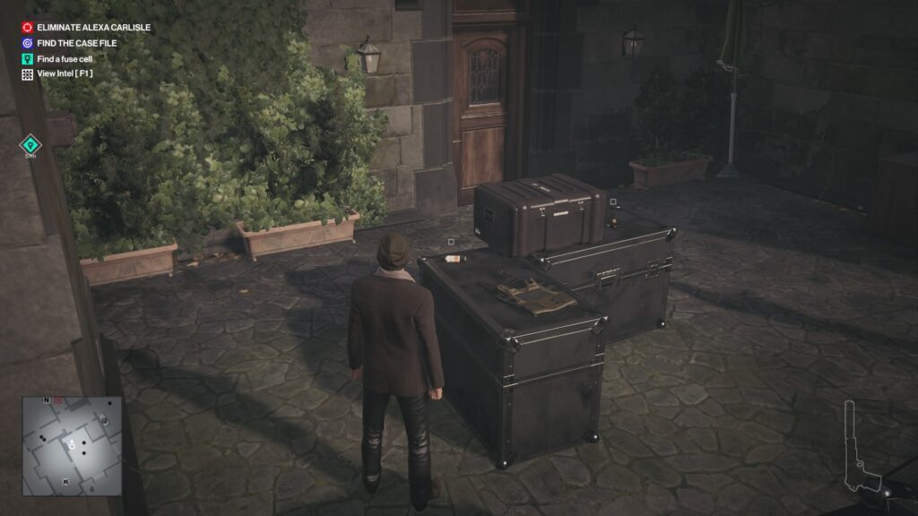 Агент 47 в Hitman стоит у ящиков во дворе